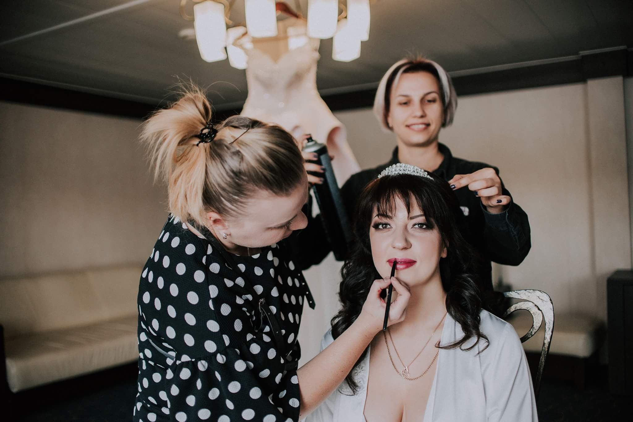 Bridal makeup artist working with bride in well-lit studio